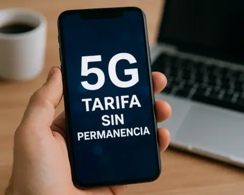 Persona sostiene un móvil con mensaje sobre tarifa 5G sin permanencia frente a portátil.